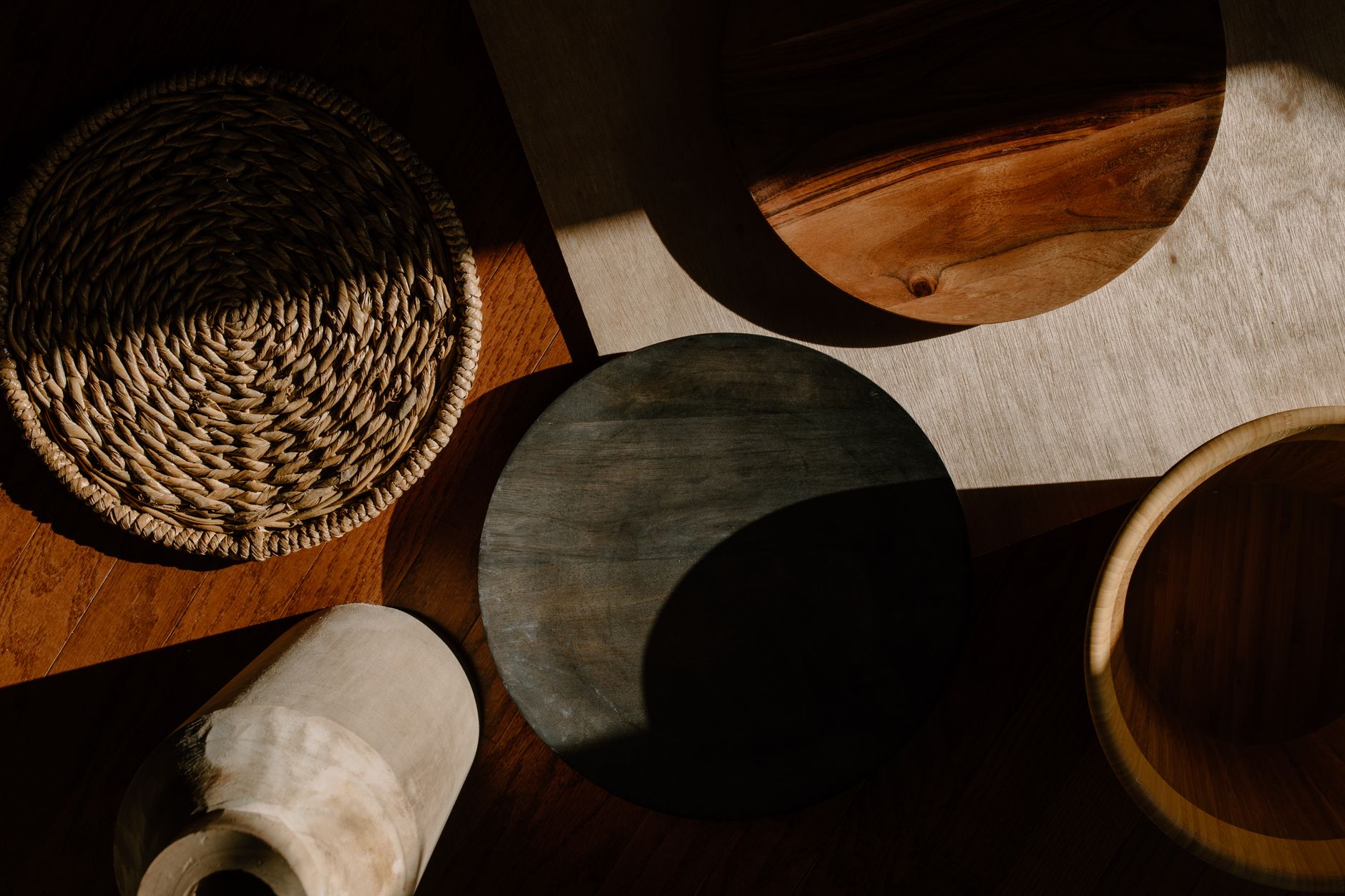 Une mise en page d'ustensiles de cuisine en bois et de matériaux tissés dans un éclairage naturel chaleureux, présentant un design minimaliste.