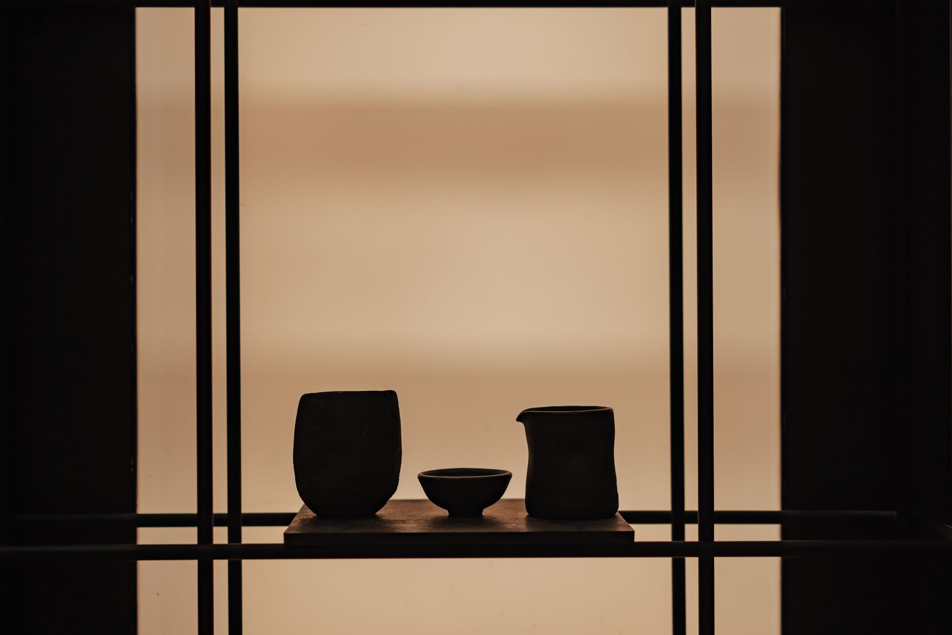Présentation minimaliste de vases en céramique sur une étagère en bois sur fond doux, mettant en valeur une décoration intérieure élégante.